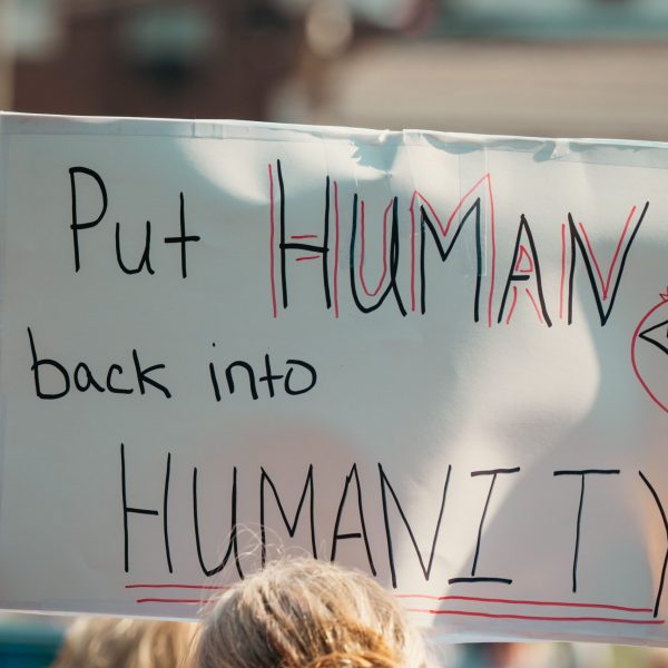pexels-photo-34355589-34355589 A protest sign with the message 'Put Human back into Humanity' during a daylight rally.
